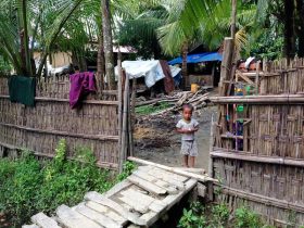 صبي من الروهنغيا خارج منزل أُعيد بناؤه حديثاً في قرية "إن بار يي" الجديدة في ولاية أراكان في ميانمار 